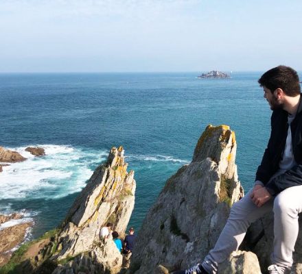 Arnau Jordà sentado en las rocas de una playa mirando al mar